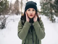 Zastanawiasz się, jaki szalik do zielonej kurtki? Ta dziewczyna w zimowym lesie ma czarną czapkę i zieloną kurtkę.