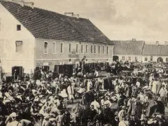 Tłum ludzi na targu w Biłgoraju, jakby żywcem wyjęty z legendy o tym mieście. W tle budynki i stragany.