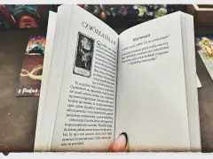 Mistycyzm i tarot marzyciela: otwarta księga z kartą "Czwórka Buław" i innymi kartami tarota.
