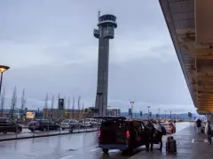 Wieża kontrolna na oslo lotnisko. Ludzie z bagażami wsiadają do vana.