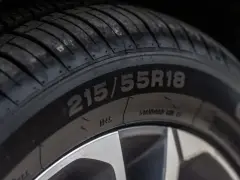 Opona samochodowa z oznaczeniem 215/55R18. Widoczny bieżnik i felga. Indeks prędkości jest kluczowy dla bezpieczeństwa.