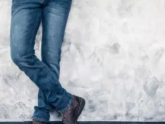 Mężczyzna w jeansach H&M, stojący przy ścianie. Rozmiarówka H&M wypada standardowo, idealnie dopasowana.