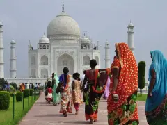 Tłum turystów, w tym kobiety w barwnych sari, zwiedza Taj Mahal. Czy Indie są bezpieczne? Tak, to popularny cel podróży.