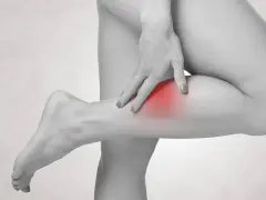 Frau tastet schmerzendes Bein ab, ein roter Fleck deutet auf einen möglichen Thrombose-Test hin.