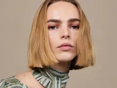 Blond włosy z przedziałkiem na bok, delikatny makijaż oczu i ust, zielony wzorzysty szal.