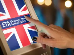 Palec dotyka ekranu z flagą Wielkiej Brytanii i napisem ETA. Czy Polacy potrzebują wizy do Wielkiej Brytanii? ETA to elektroniczne zezwolenie na podróż.