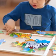 Chłopiec układa kolorowe puzzle z zwierzątkami. To świetne puzzle co rozwijają wyobraźnię i zdolności manualne.