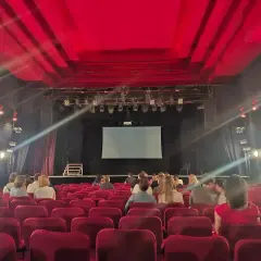 Widownia w Teatrze Palladium w Warszawie. Czerwone fotele i scena z ekranem czekają na widzów.