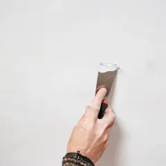 Mano che stende stucco su una parete per la pittura soffitto.