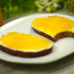 Zwei Scheiben Brot mit Frischkäse und leuchtend gelber, selbstgemachter low carb Marmelade.