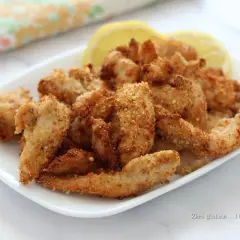 Straccetti di pollo croccanti e dorati, cotti in friggitrice ad aria, serviti con spicchi di limone.