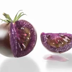 Un pomodoro viola, tagliato a metà, rivela la sua polpa succosa e un'insolita fetta con gocce di succo viola.