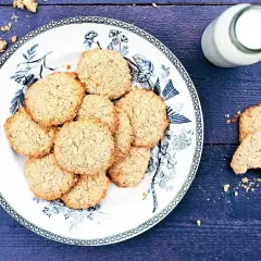 En tallrik med hembakade havrekakor, perfekt för ett enkelt havrekakor recept. En flaska mjölk står bredvid.