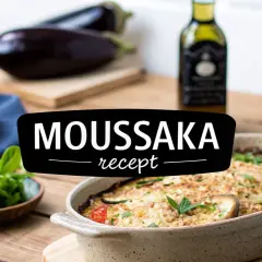 En ugnsbakad moussaka i en keramikform, med aubergine, tomater och örter. Texten "MOUSSAKA recept" syns tydligt.