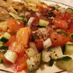 En saftig coban salata med tomater, gurka och lök, kryddad med sumak, serveras bredvid grillad kyckling.