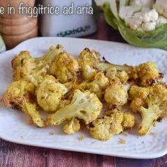 Cavolfiore dorato e croccante, cotto in friggitrice ad aria, servito su un piatto bianco.