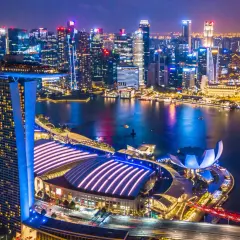 Nocny widok na Singapur z oświetlonymi drapaczami chmur i Marina Bay Sands. Miasto tętni życiem, a jego rozwój, jak singapur szczepienia, świadczy o postępie.