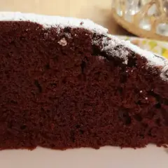 Una fetta di torta al cioccolato soffice, spolverata di zucchero a velo. Un'idea golosa per una torta mascarpone e cioccolato.