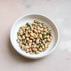 Eine Schüssel mit gekochten, hellen Bohnen, verfeinert mit gehackter Petersilie. Diese Fagioli Borlotti sind ein köstlicher deutscher Klassiker.