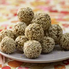 Ein Haufen köstlicher Energy Balls, umhüllt von Sesam, auf einem Teller. Perfekt für einen schnellen Energieschub!