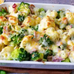 Ein herzhafter blumenkohl brokkoli auflauf mit geschmolzenem Käse und Schinkenstücken, frisch aus dem Ofen.