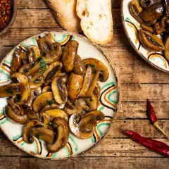 Plato de setas a la plancha con ajo, pan y guindillas secas. Un delicioso aperitivo rústico.