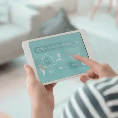 Un hombre controla su hogar inteligente desde una tablet, un vistazo a la historia de la domótica.