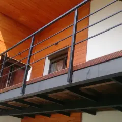Nowoczesny balkon dostawny z metalową balustradą i drewnianą podłogą. Sprawdź, jaka balkon dostawny cena Cię czeka!