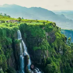 Wodospad na zielonym klifie, plantacje herbaty i domki na wzgórzu. Widok zapierający dech w piersiach, idealny na wiza Sri Lanka.