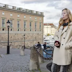 Sara Mac Key, med hörlurar runt halsen, tar en cigarettpaus vid vattnet i Stockholm.