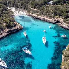 Traumhafte Bucht mit türkisfarbenem Wasser, Segelbooten und einem Strand – ein echter Mallorca Geheimtipp für unvergessliche Urlaubstage.