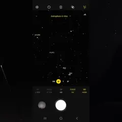 Mężczyzna robi zdjęcie nocnego nieba z Saturnem i Plutonem za pomocą telefonu Samsung. Tryb Astrophoto ustawiony na 4 minuty.