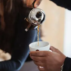 Eine French Press wird benutzt, um frisch gebrühten Filterkaffee in eine Tasse zu gießen.