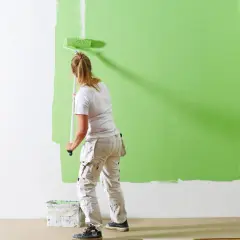 En person målar en vägg grön. Undrar du varför det blir ränder när jag målar? Här ser du hur färgen täcker ojämnt.