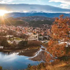 Widok na miasteczko nad jeziorem, góry w tle. Idealne miejsce, gdzie na wakacje w sierpniu, choć liście drzew już brązowe.