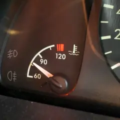 Le témoin de température moteur s'allume, indiquant une **cause surchauffe moteur essence**. Le thermomètre est proche de 120°C.