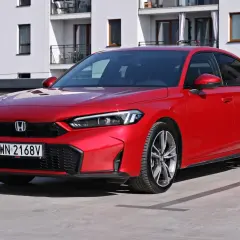Czerwony Honda Civic Si na parkingu przed nowoczesnym budynkiem. Sportowy wygląd i dynamiczna linia nadwozia.