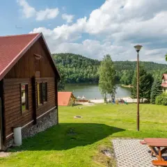Drewniane domki nad jeziorem w Dolnośląskim. Piękny krajobraz z zielonymi wzgórzami i jeziorem.
