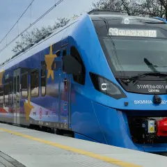 Niebieski pociąg SKM z motywem gwiazd Unii Europejskiej na boku, gotowy do odjazdu.