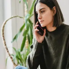 Młoda kobieta, jobseeker, rozmawia przez telefon, jej mina sugeruje rezygnację.