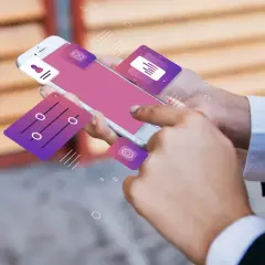 Dłonie trzymające smartfon z ikonami aplikacji, sugerujące funkcjonalność dual standby.