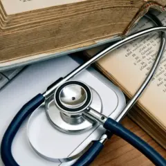 Libri antichi e uno stetoscopio su una tastiera, evocano lo studio della medicina legale.