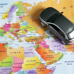 Une petite voiture grise sur une carte d'Europe. Conduite à gauche quel pays ? L'image suggère un voyage en Europe, où la conduite à gauche est la norme dans de nombreux pays.