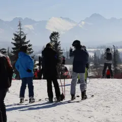 Grupa narciarzy na stoku podziwia piękne widoki Tatr. Idealne ferie zimowe!