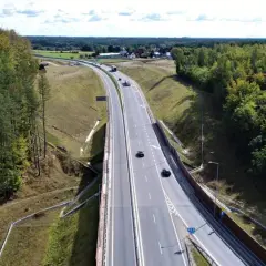 Droga krajowa 22 przecina gęsty las. Samochody poruszają się po wielopasmowej jezdni, otoczonej zielenią.