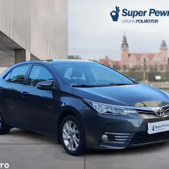 Szary sedan Toyota Corolla używane z salonu, z logo "Super Pewniak" na tablicy rejestracyjnej.