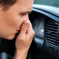 Man håller för näsan i bilen, en tydlig signal att det är dags att ta bort dålig lukt i bil.