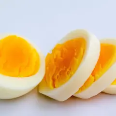 Ein halbes und drei Scheiben hartgekochtes Ei auf weißem Hintergrund. Ein Ei hat viel Protein.