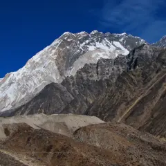 Majestatyczny Mount Everest w śnieżnej koronie, widok z bazy pod Everestem. Surowe, skaliste zbocza i błękitne niebo.