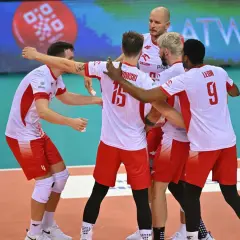 Siatkarze reprezentacji Polski w biało-czerwonych strojach świętują na boisku.